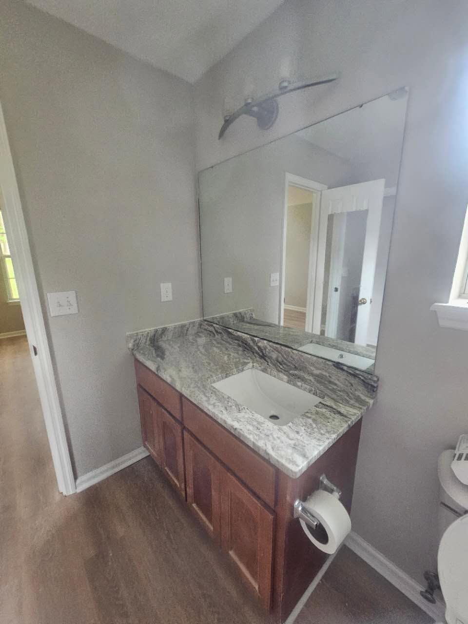 A bathroom with a sink, toilet, and mirror.