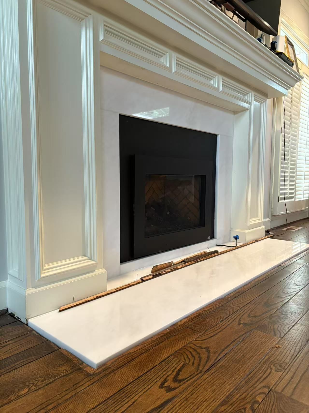 A fireplace is being built in a living room with hardwood floors.
