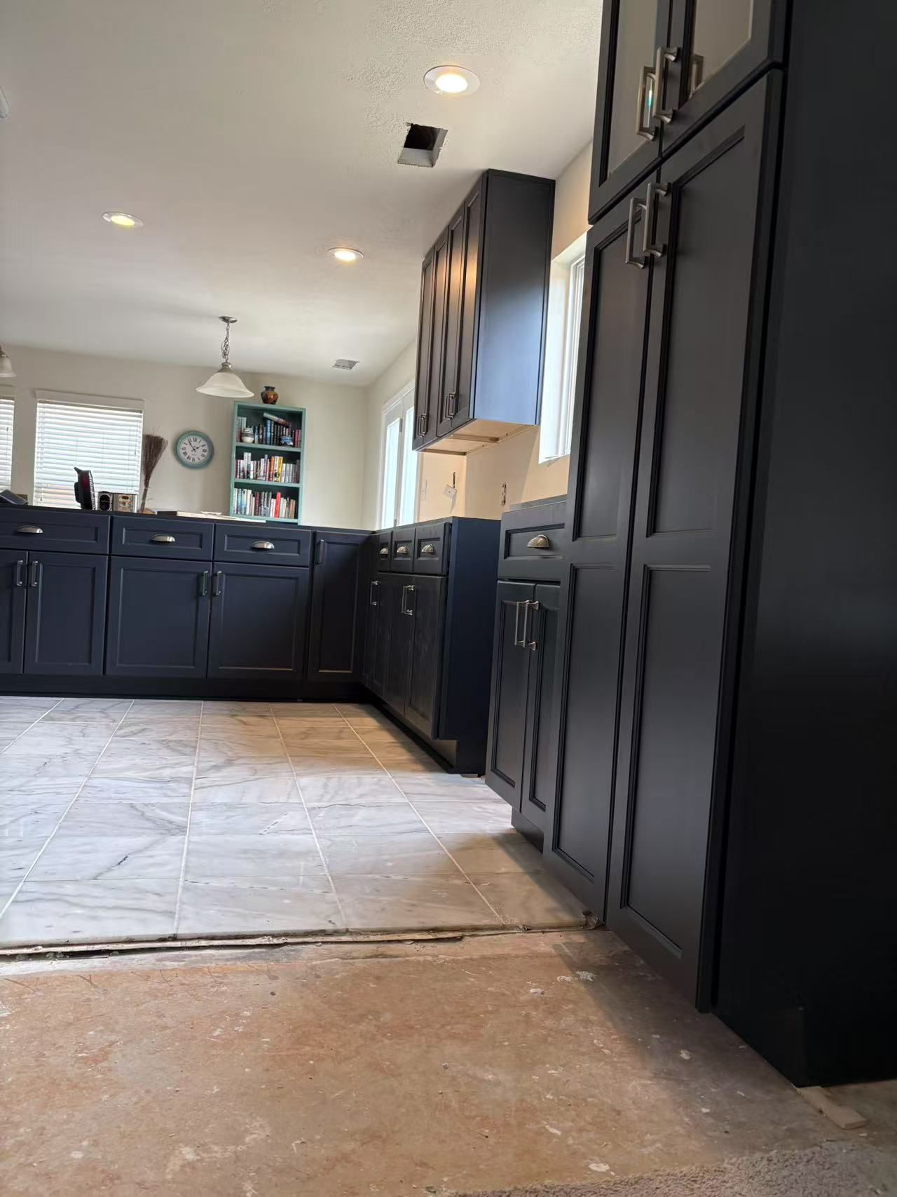 A kitchen with black cabinets and a tiled floor.