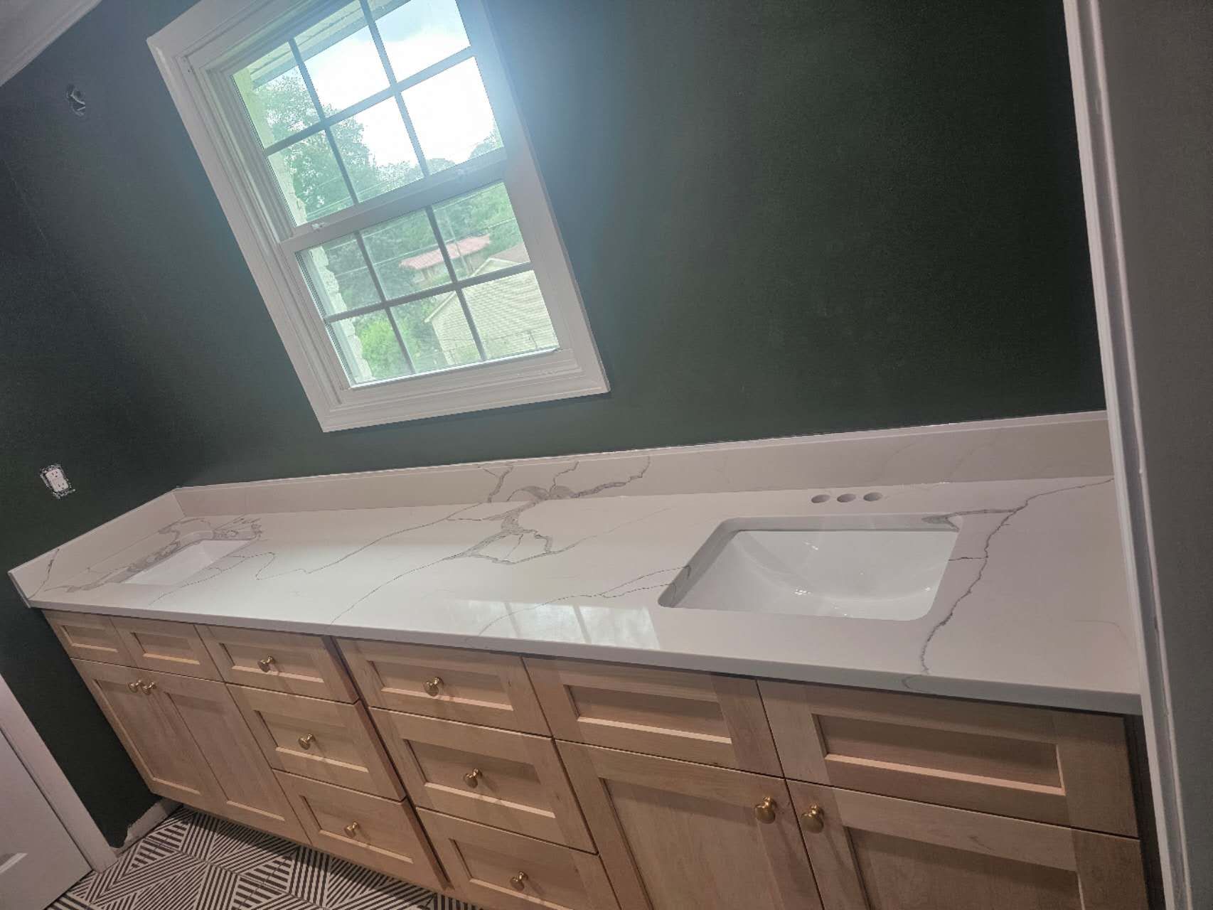 A bathroom with a sink, cabinets, and a window.