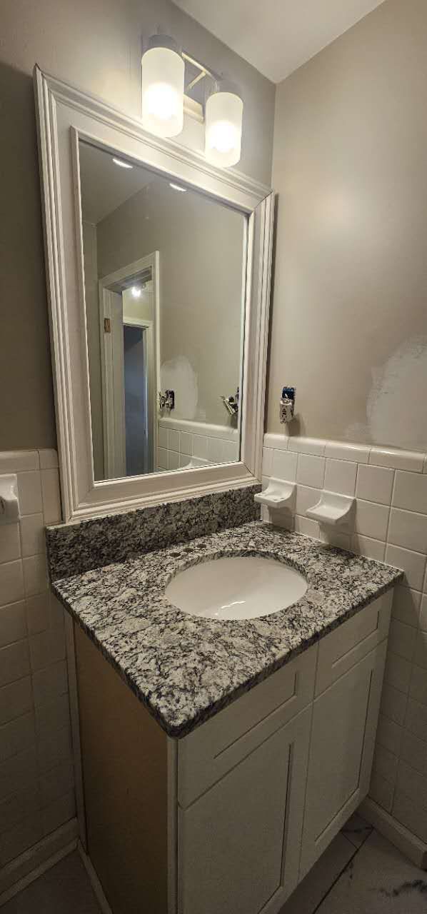 A bathroom with a sink and a large mirror.