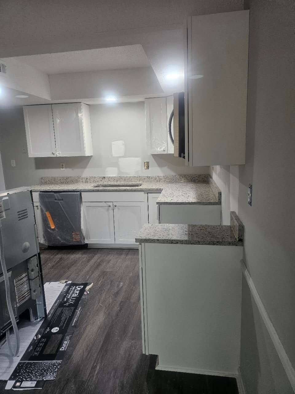 A kitchen with white cabinets and granite counter tops.