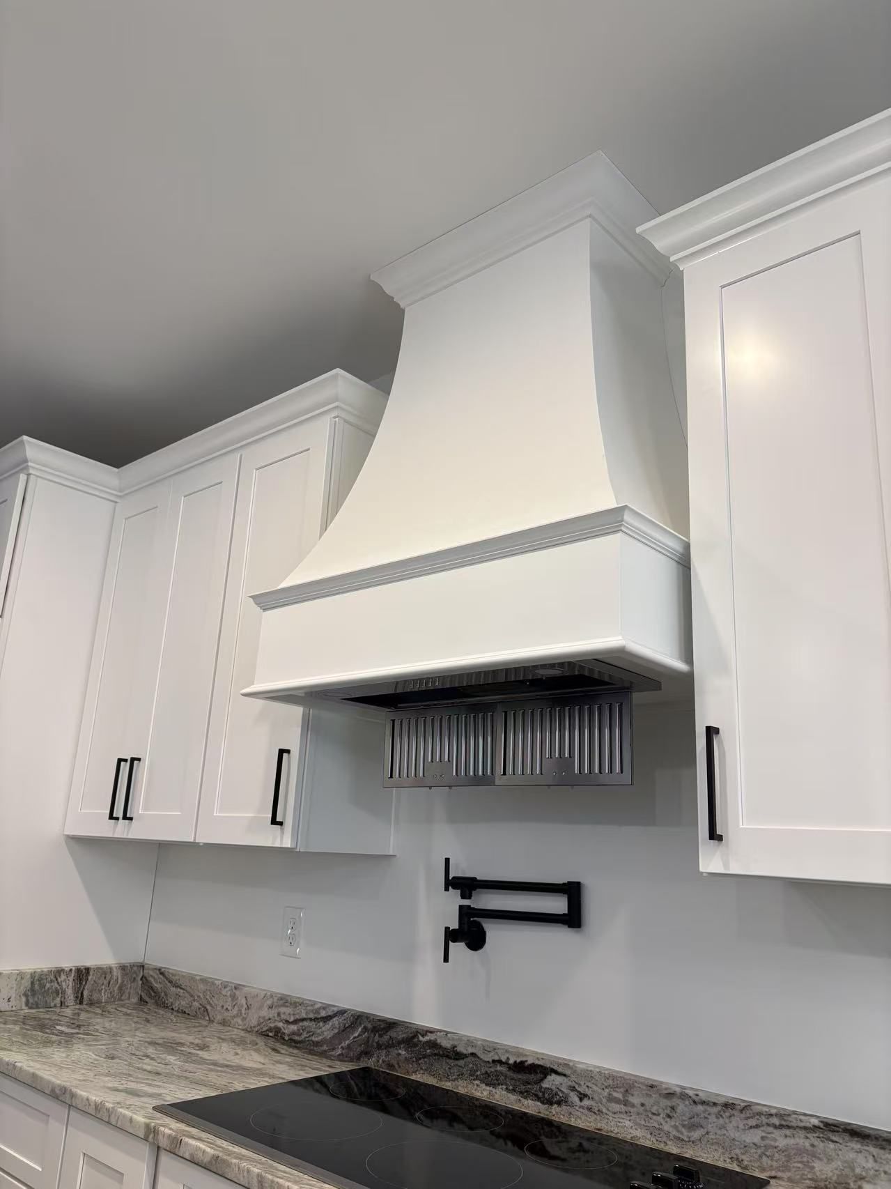 A kitchen with white cabinets and a stove top oven.