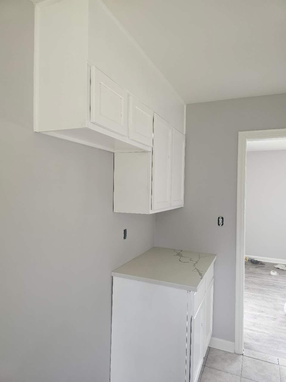 A kitchen with white cabinets and a refrigerator.