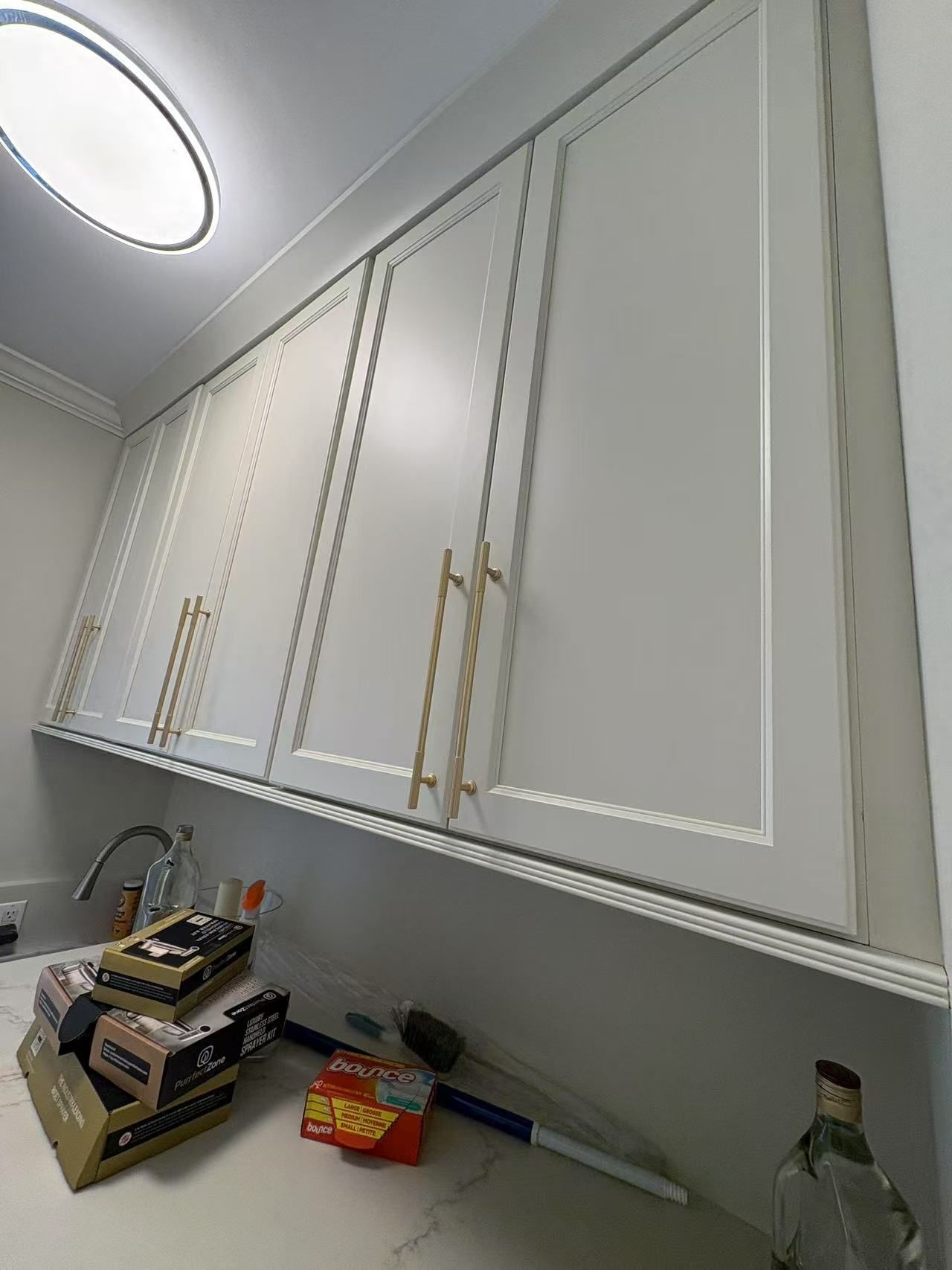 A kitchen with white cabinets and gold handles is being remodeled.