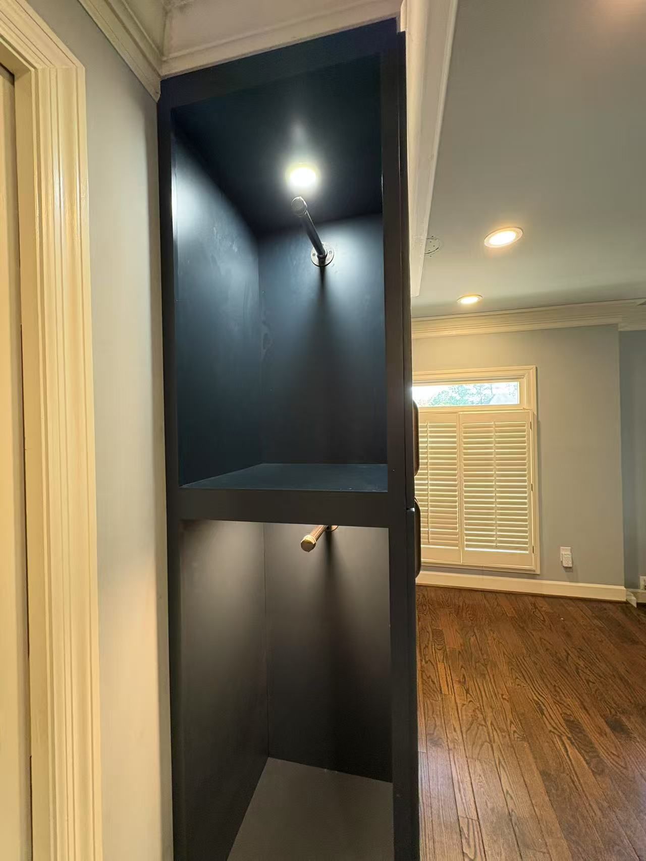 There is a shelf in the corner of the room with a light on it.