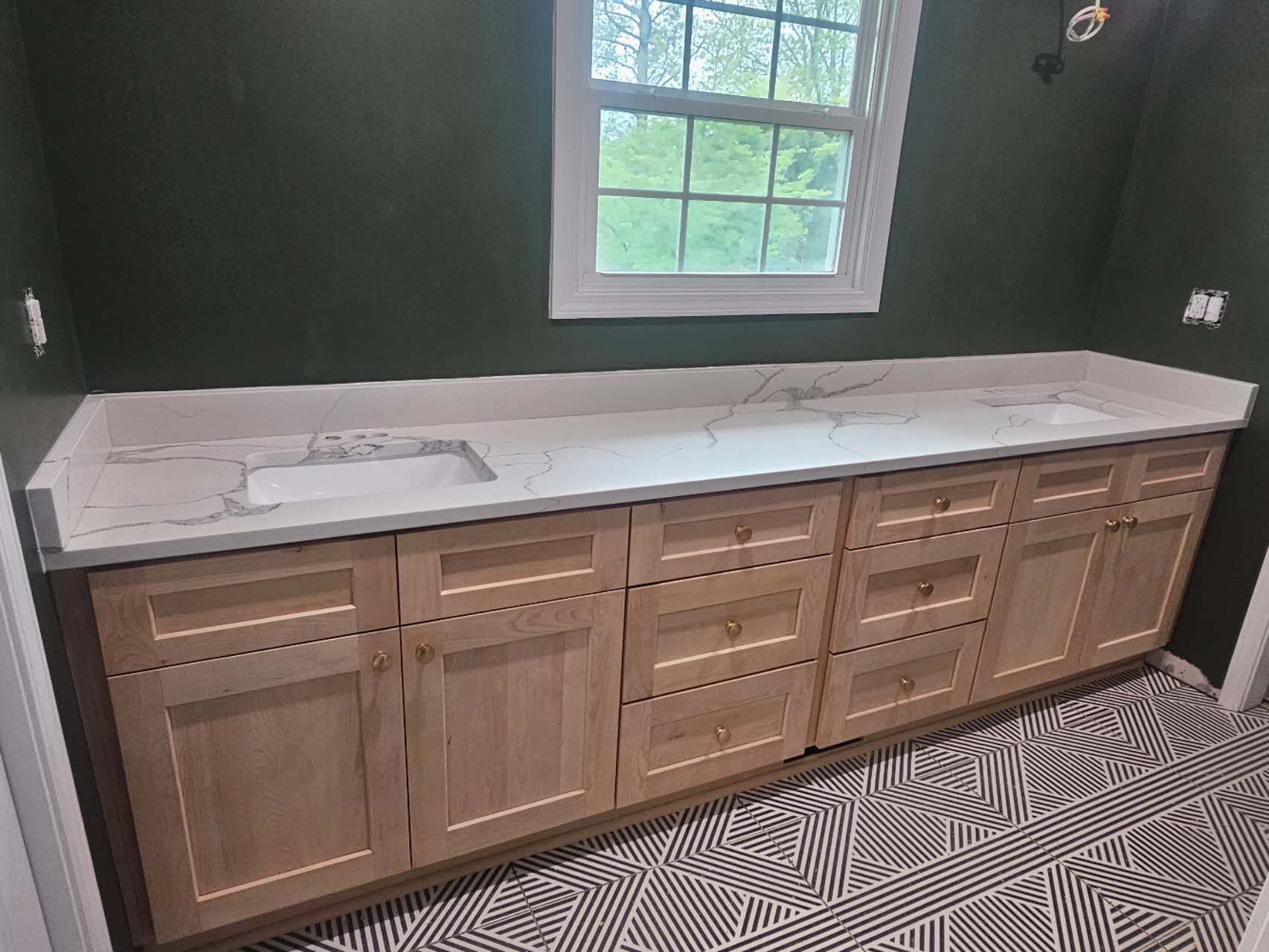 A bathroom with a sink, cabinets, and a window.