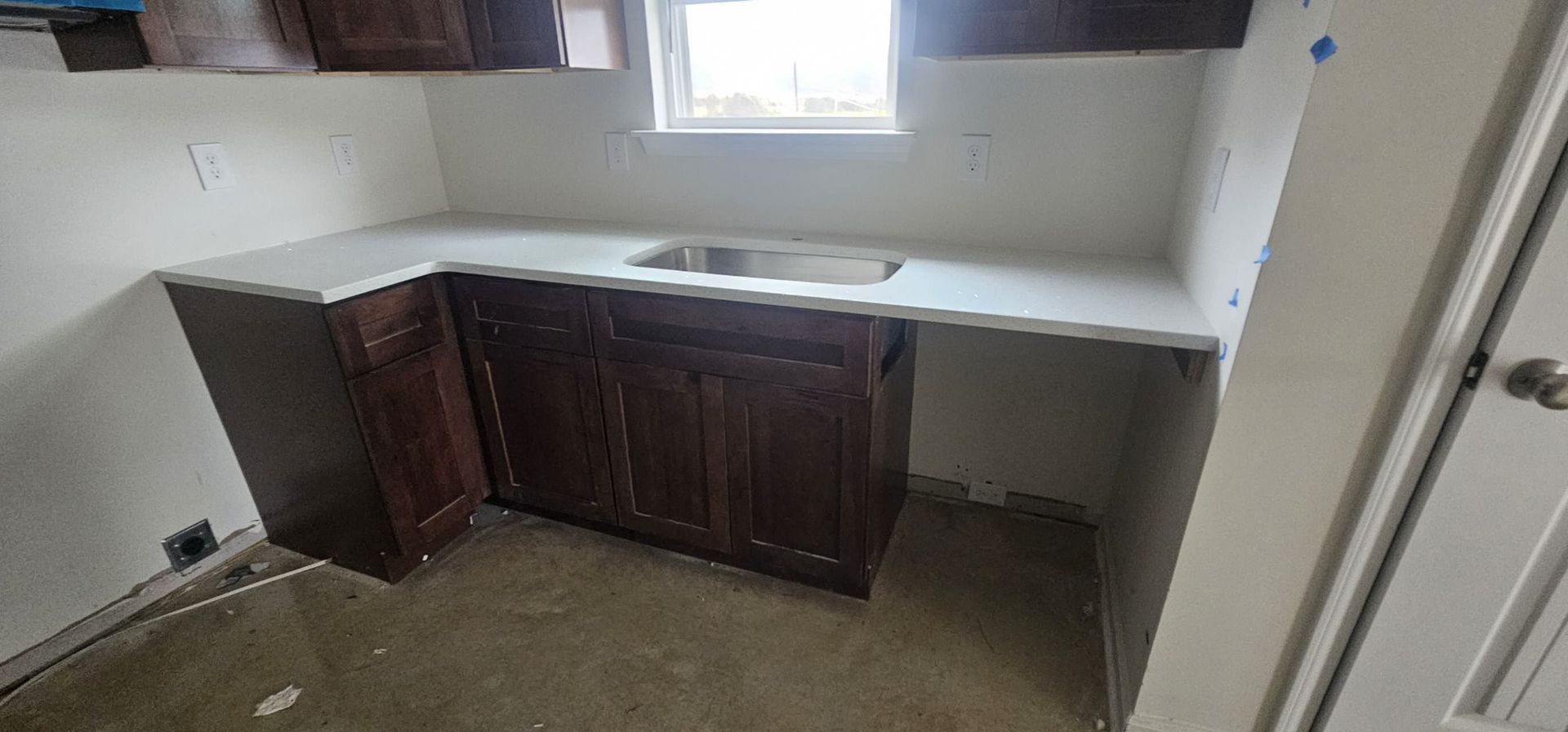 A kitchen with a sink, cabinets, and a window.