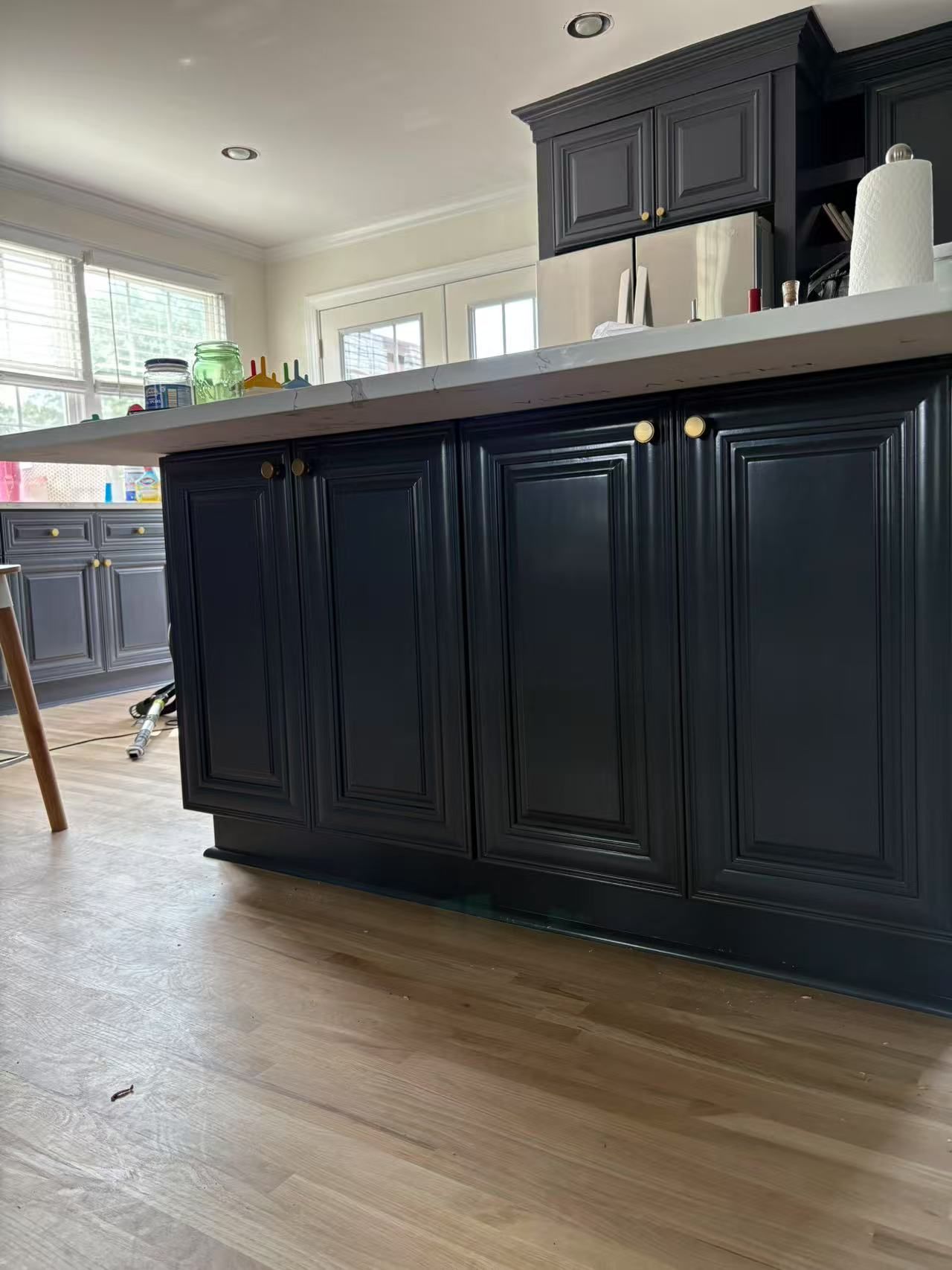 A kitchen with black cabinets and a wooden floor.