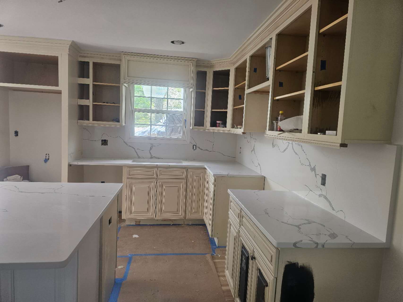 A kitchen with white cabinets and white counter tops is being remodeled.