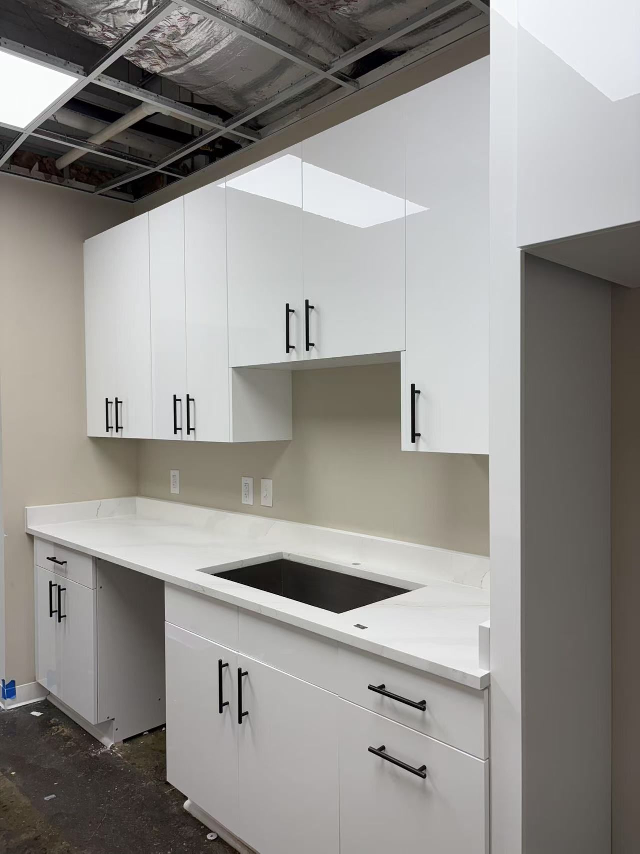 A kitchen with white cabinets, a sink, and a counter.