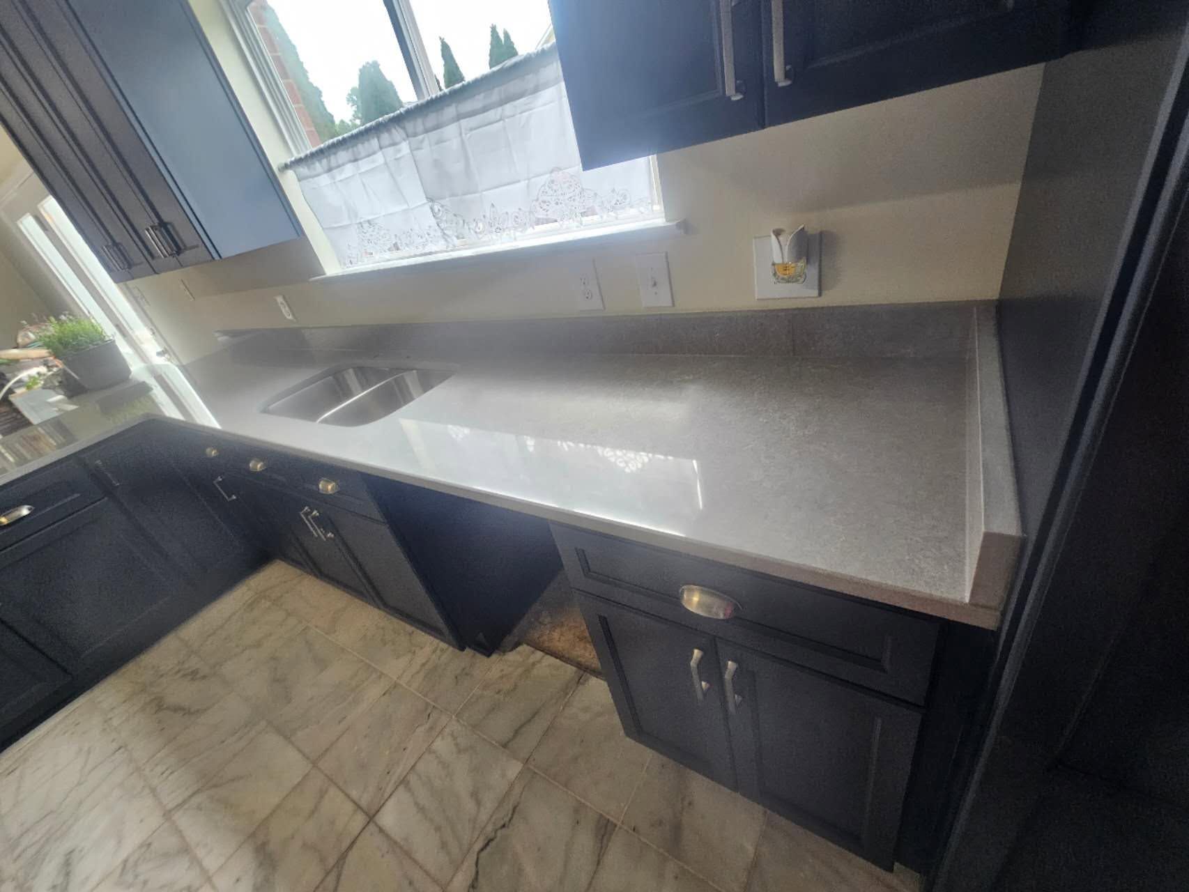 A kitchen with black cabinets, a sink, and a window.