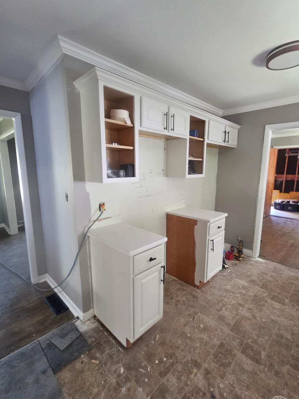 A kitchen with white cabinets and wooden cabinets.