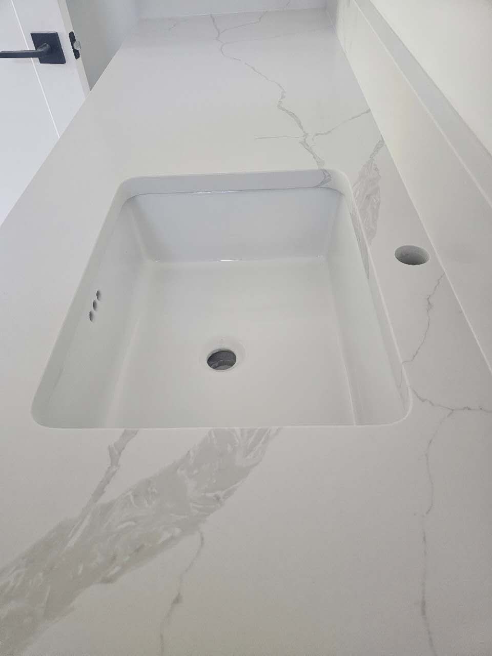 A white sink is sitting on top of a white counter.