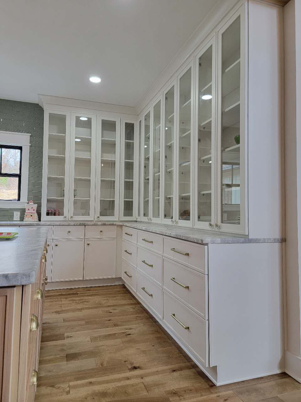 A kitchen with white cabinets and glass doors.
