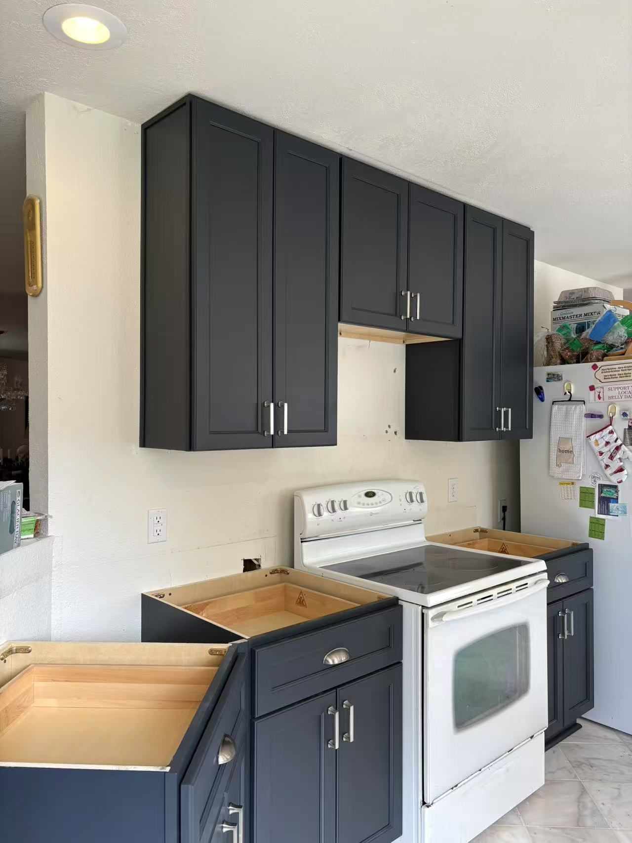 A kitchen with black cabinets, a white stove, and a white refrigerator.