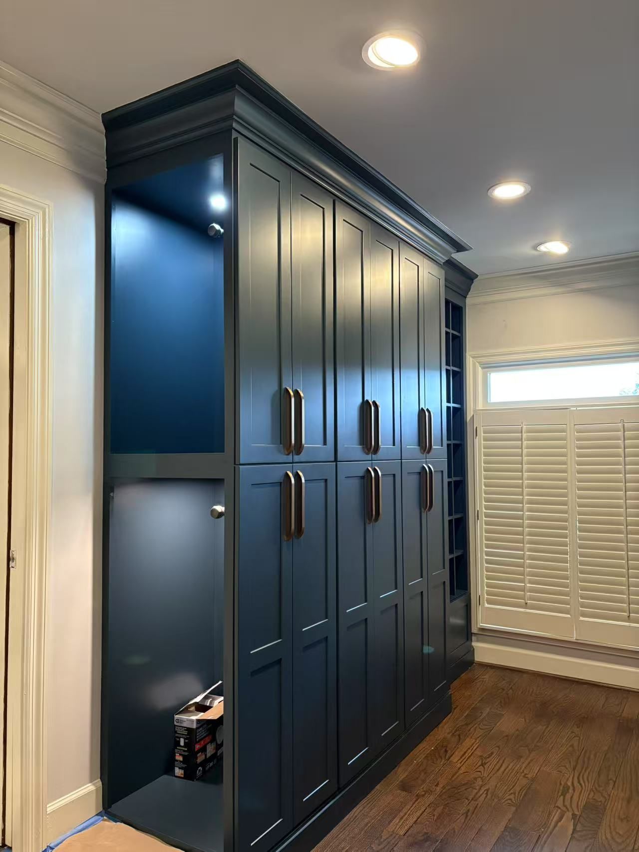 A room with a lot of cabinets and shutters on the windows.