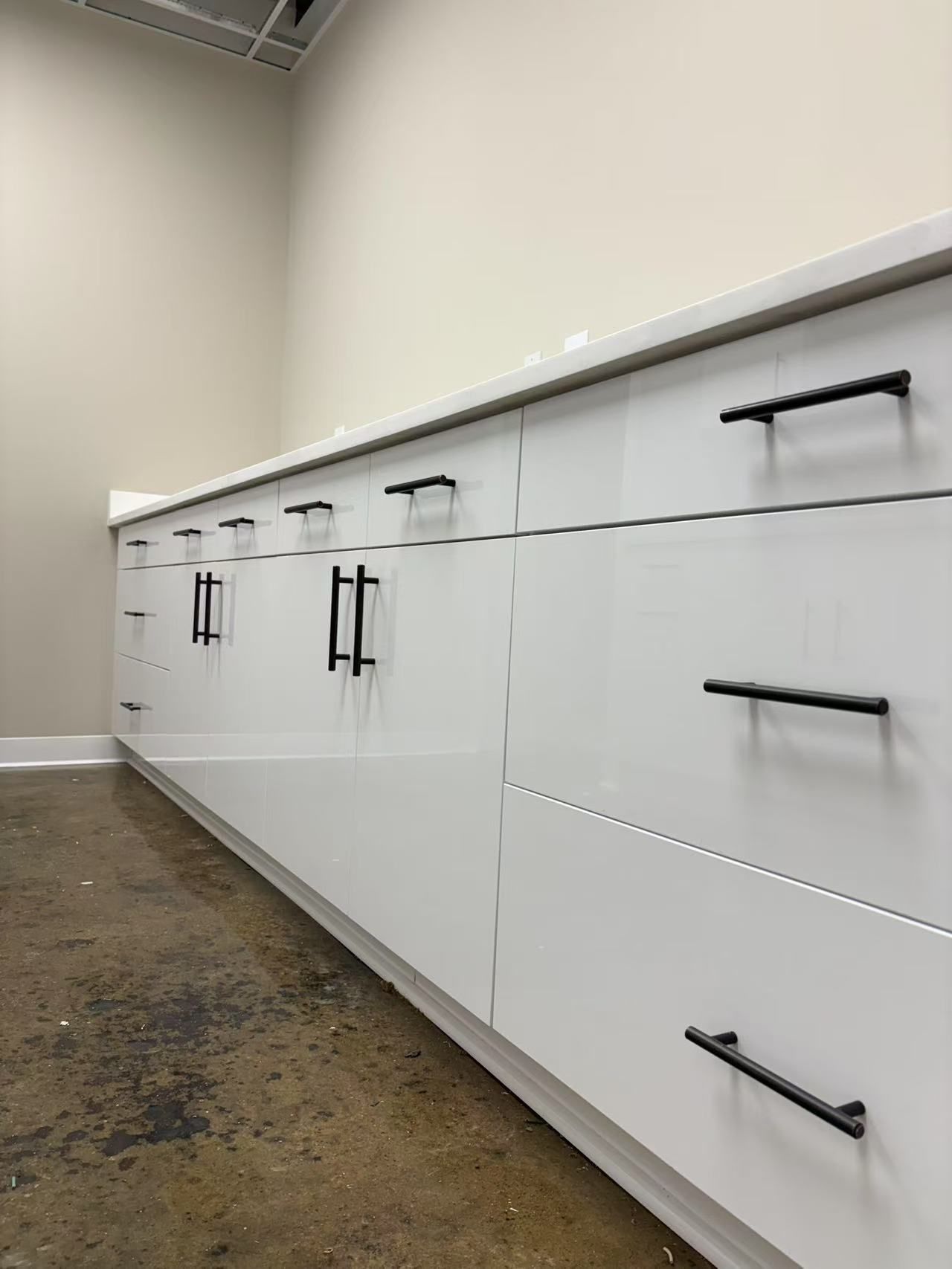 A row of white cabinets with black handles in a kitchen.