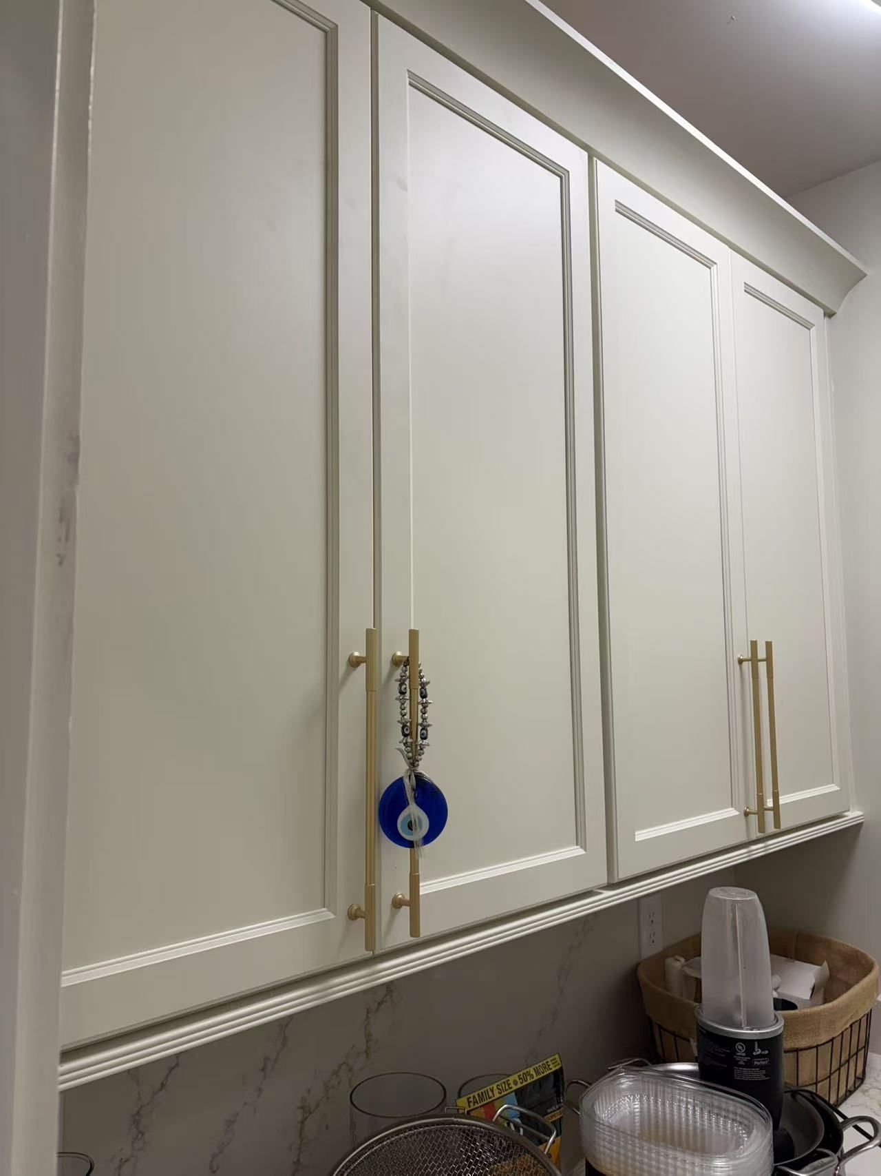 A kitchen with white cabinets and a blue evil eye on the door.