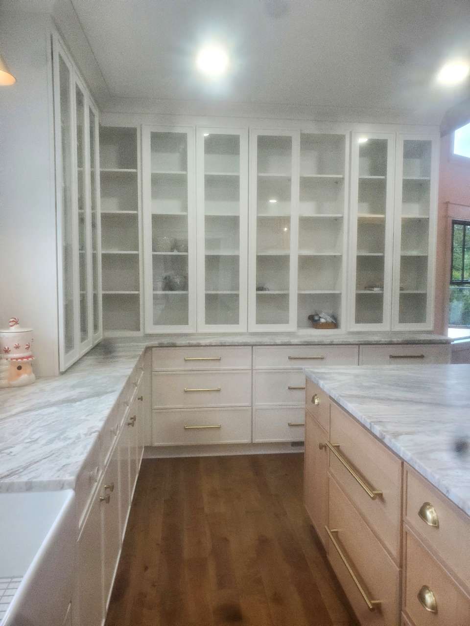 A kitchen with white cabinets and marble counter tops.