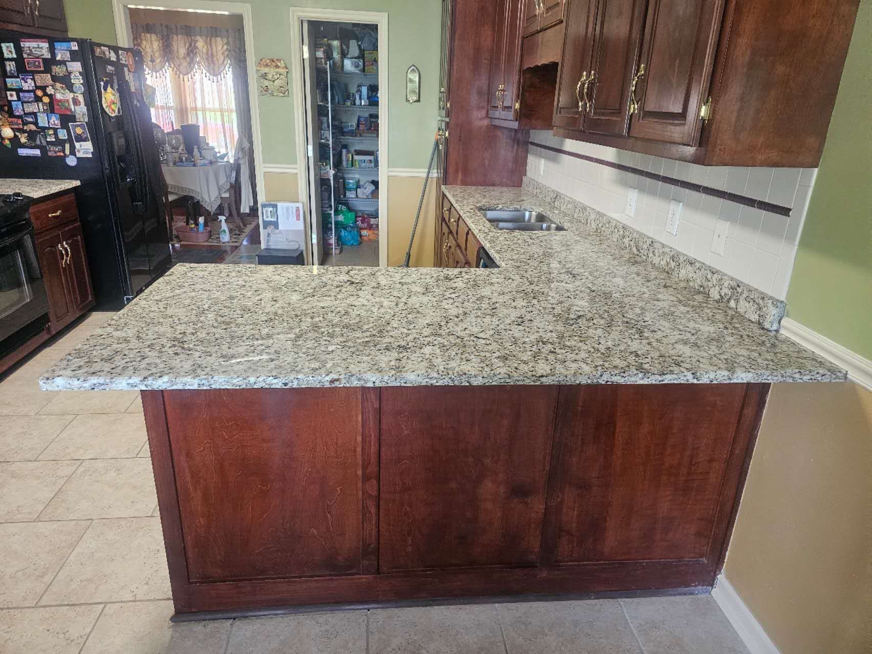 A kitchen with granite counter tops and wooden cabinets.
