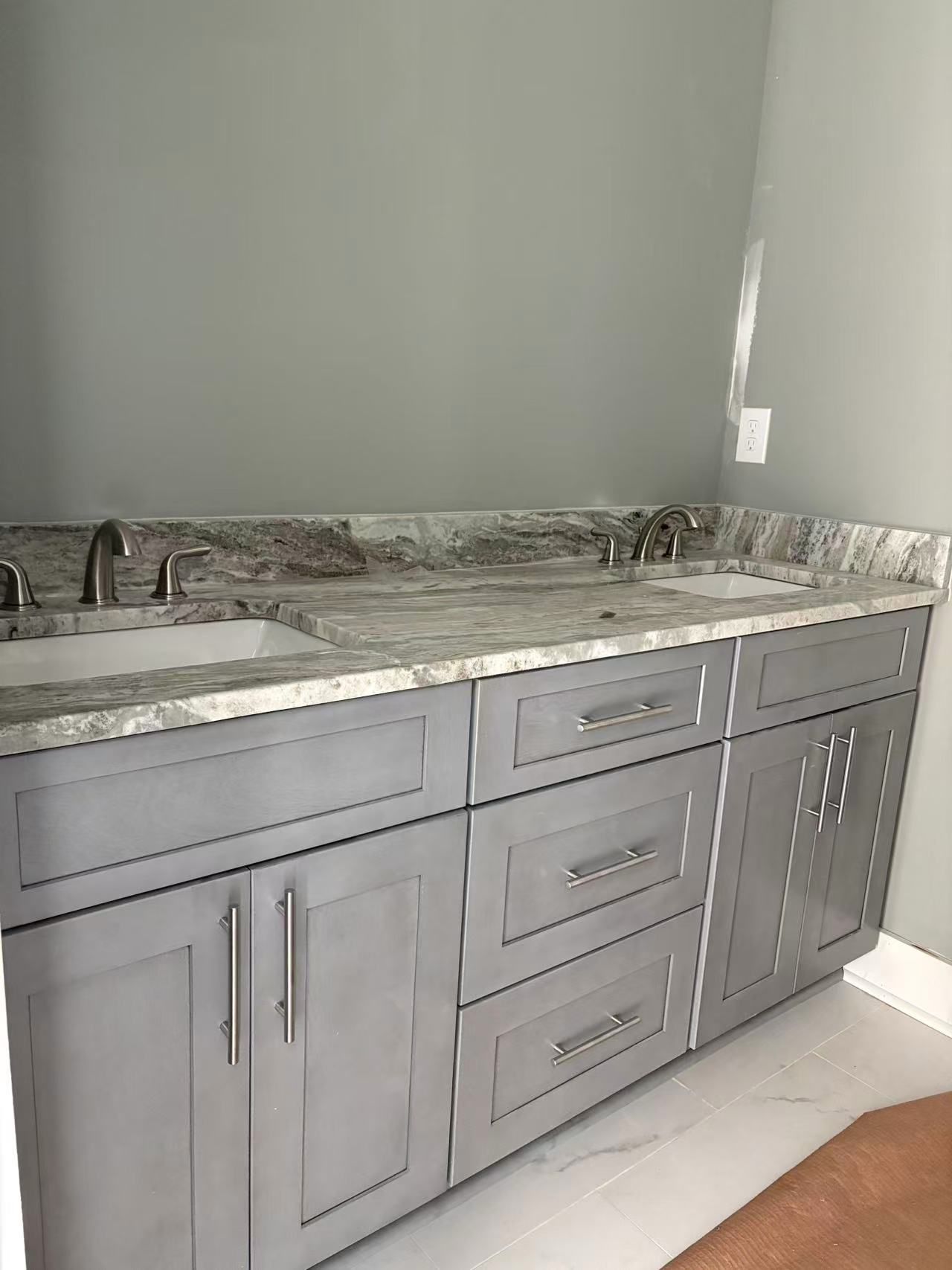 A bathroom with two sinks and gray cabinets.