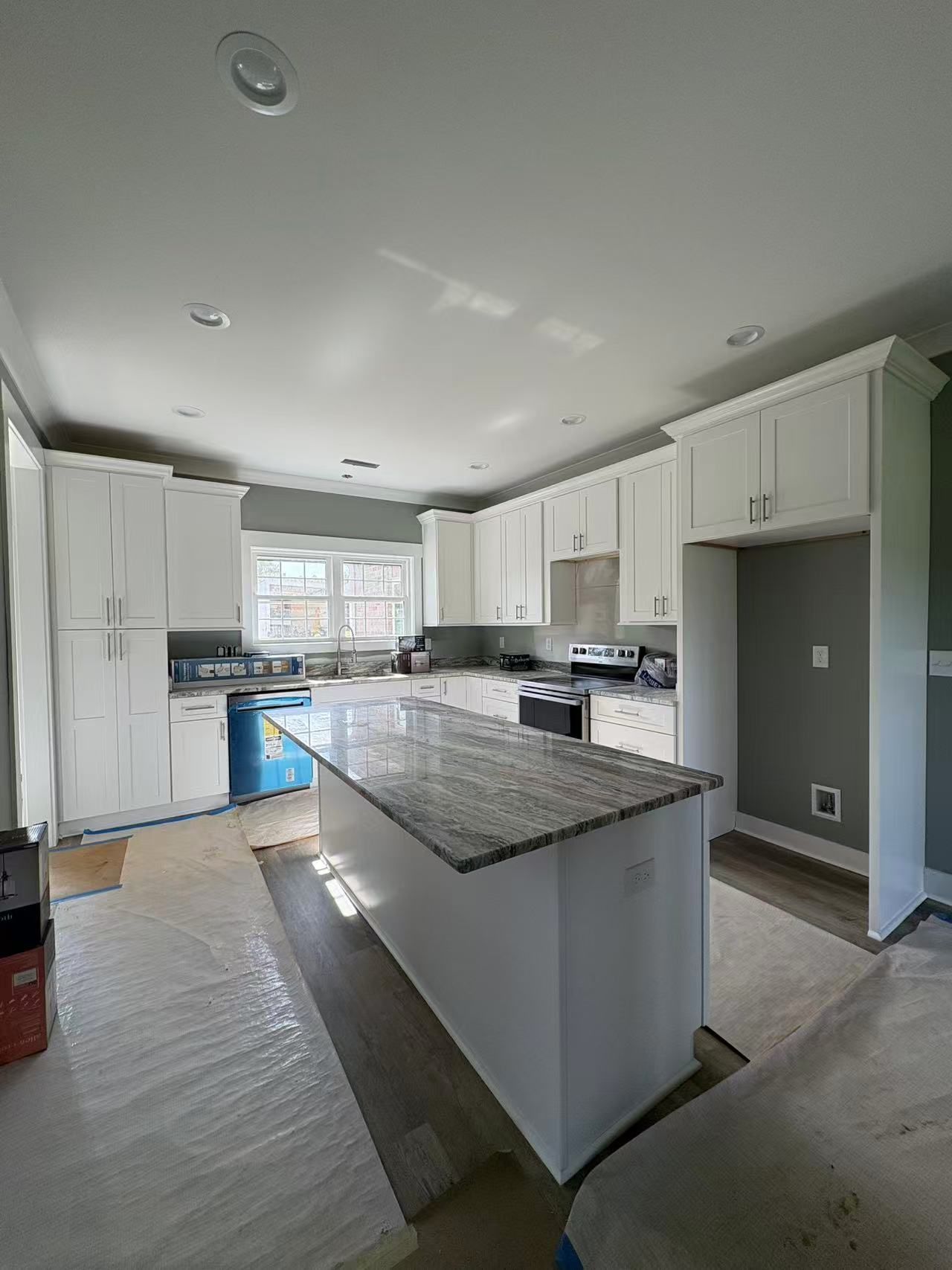 A kitchen with white cabinets and granite counter tops is being remodeled.