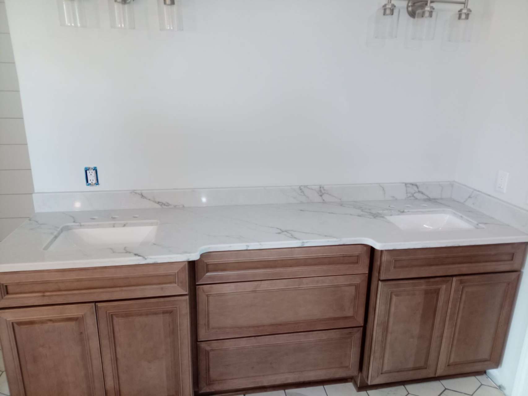 A bathroom vanity with wooden cabinets and a marble counter top.