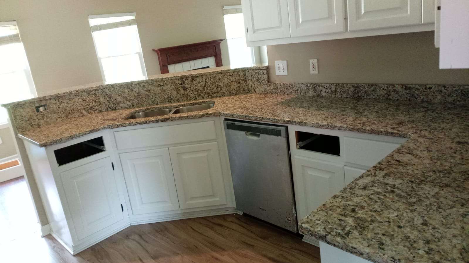 A kitchen with granite counter tops , white cabinets and a stainless steel dishwasher.