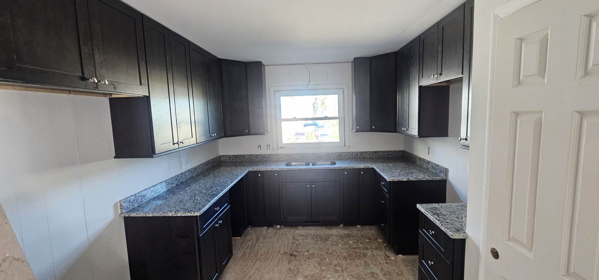 A kitchen with black cabinets and granite counter tops.