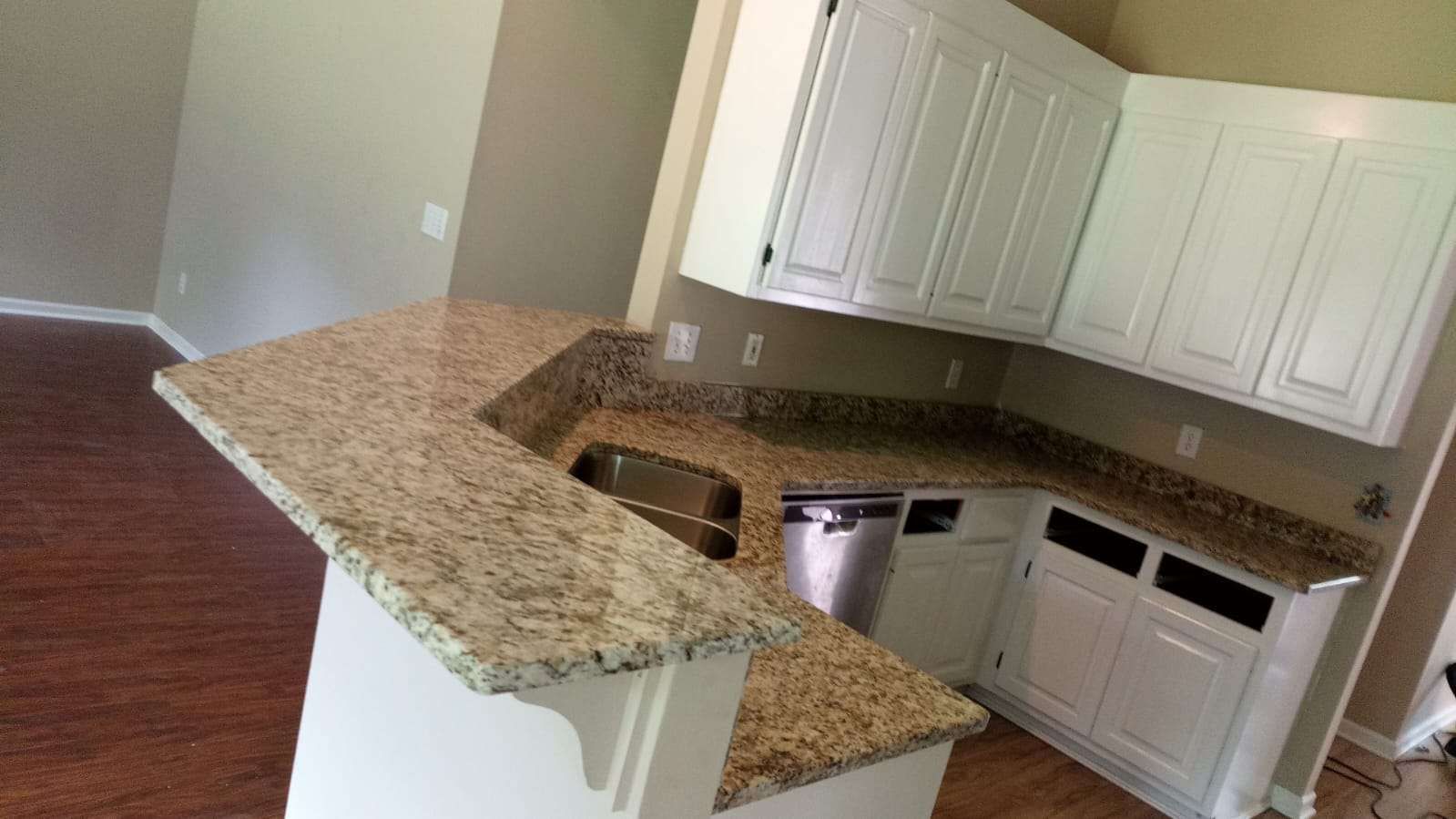 An empty kitchen with granite counter tops and white cabinets.