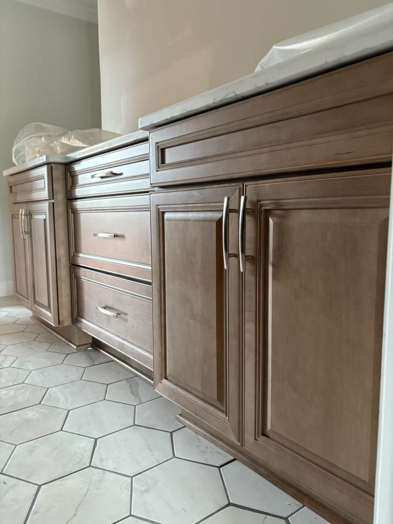 A bathroom with wooden cabinets and a hexagonal tile floor.