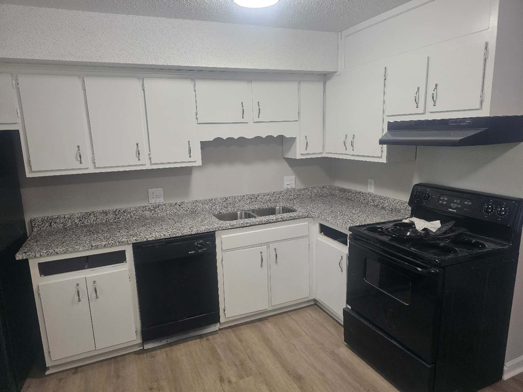 A kitchen with white cabinets, black appliances, and granite counter tops.