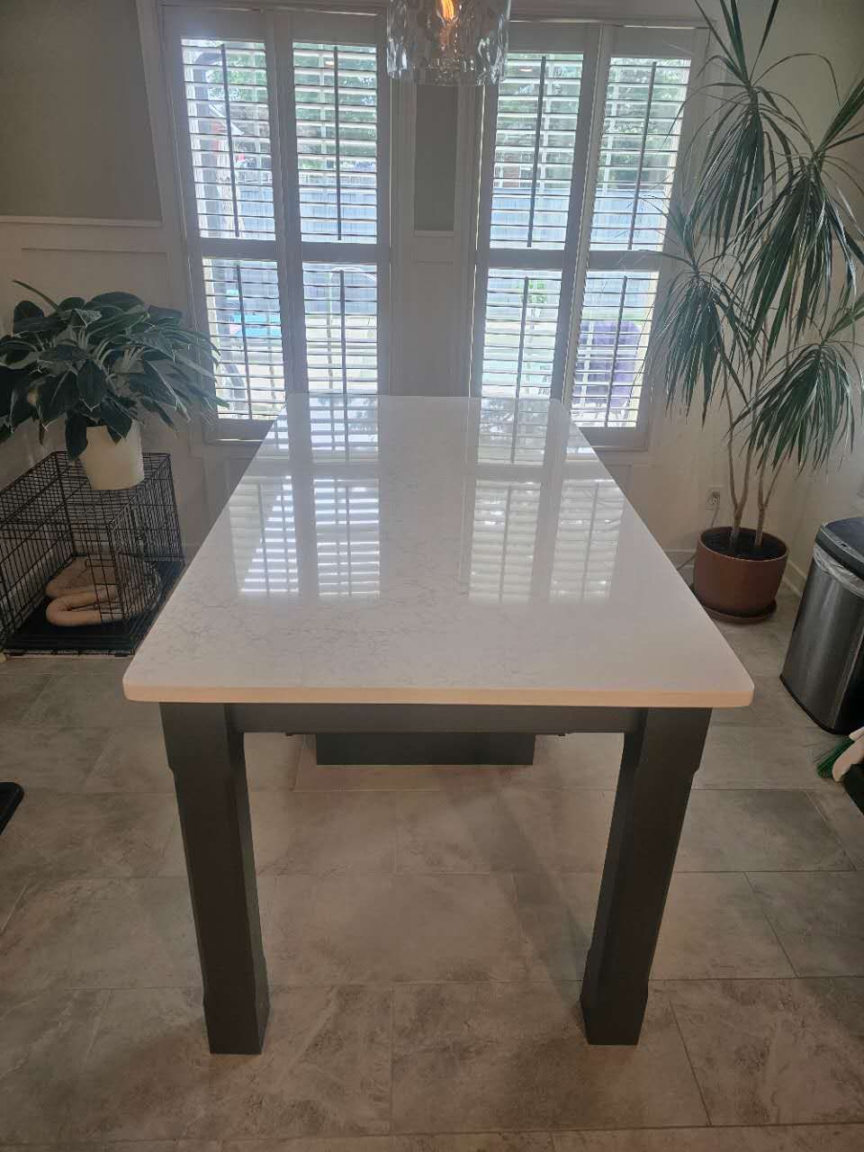 A white table with black legs is sitting in a room next to a window.