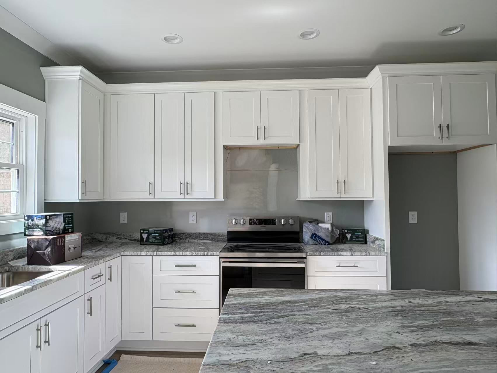 A kitchen with white cabinets, granite counter tops, and a stove.