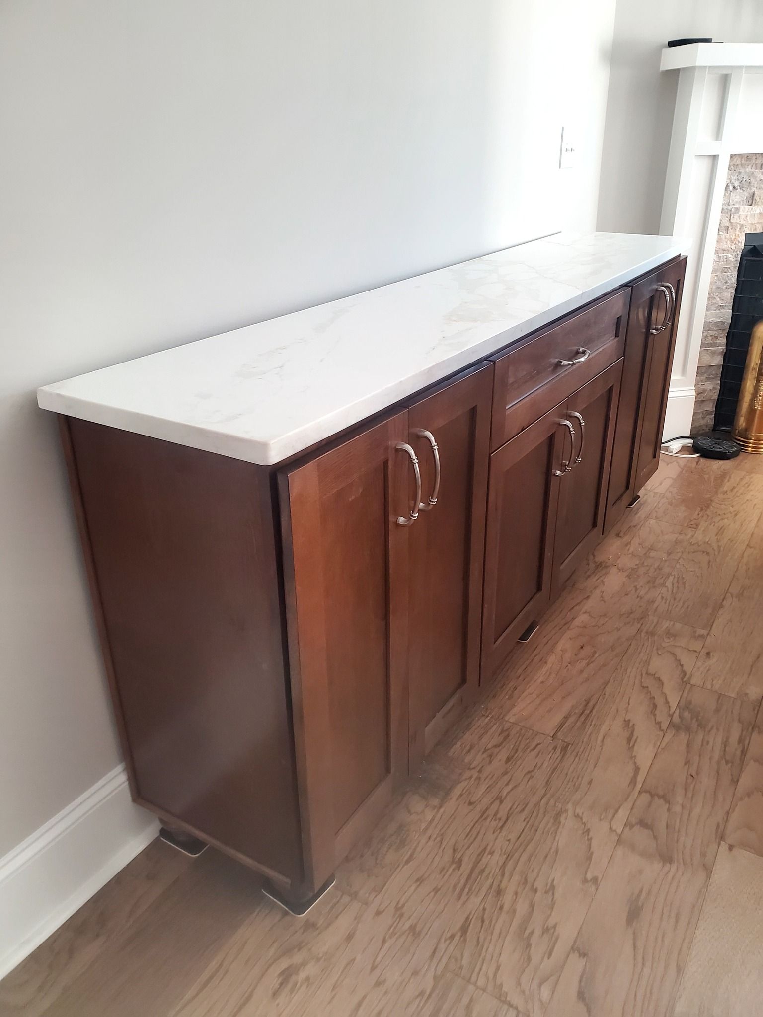 A long wooden cabinet with a white counter top in a living room.