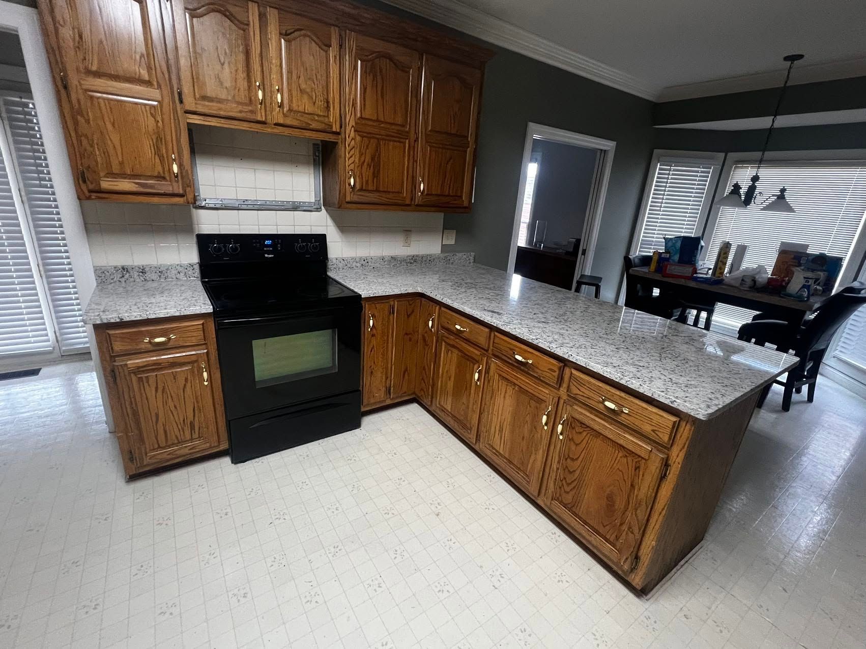 A kitchen with wooden cabinets, granite counter tops, and a black stove.