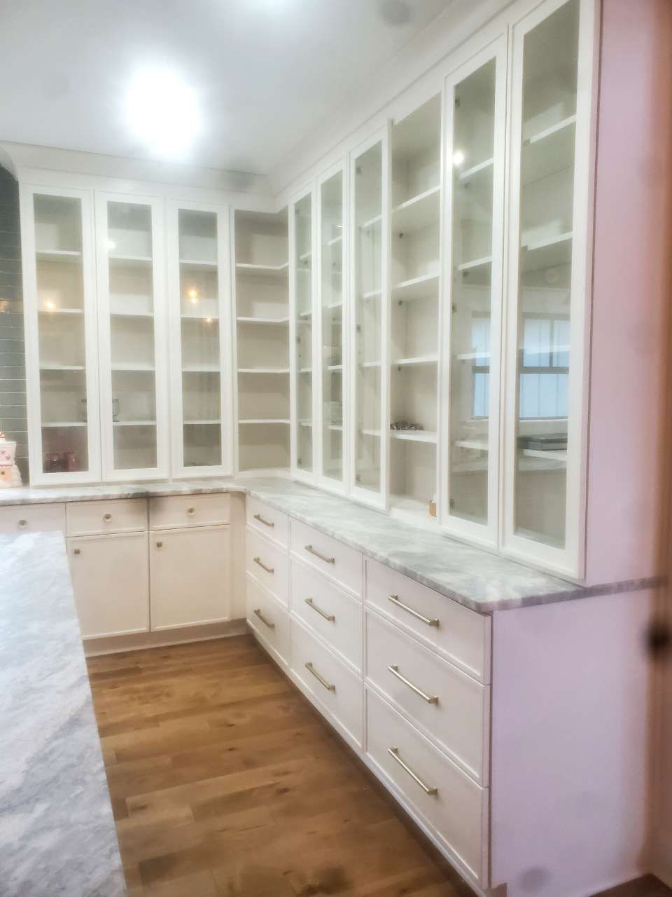 A kitchen with white cabinets and glass doors.