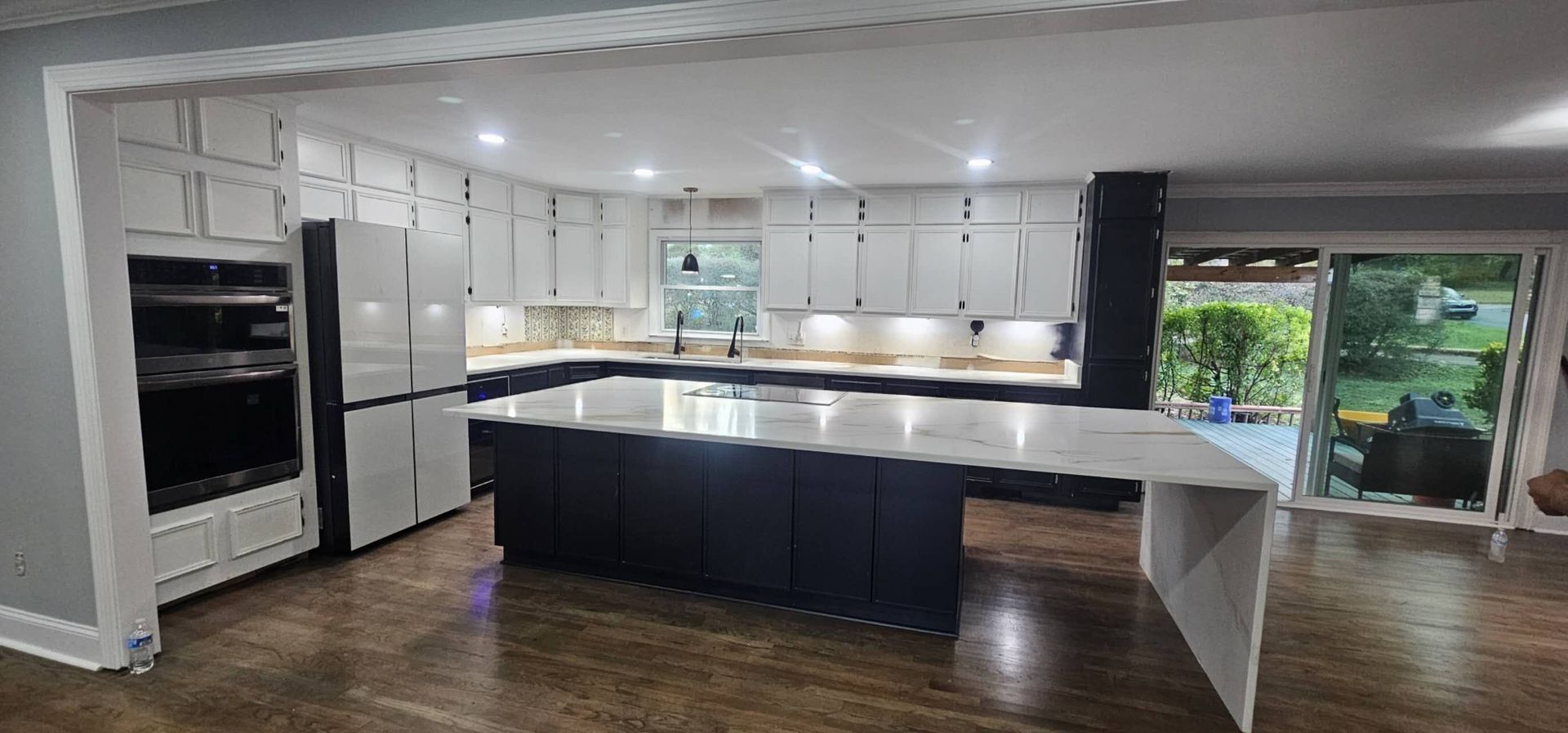 A kitchen with white cabinets and a large island in the middle.