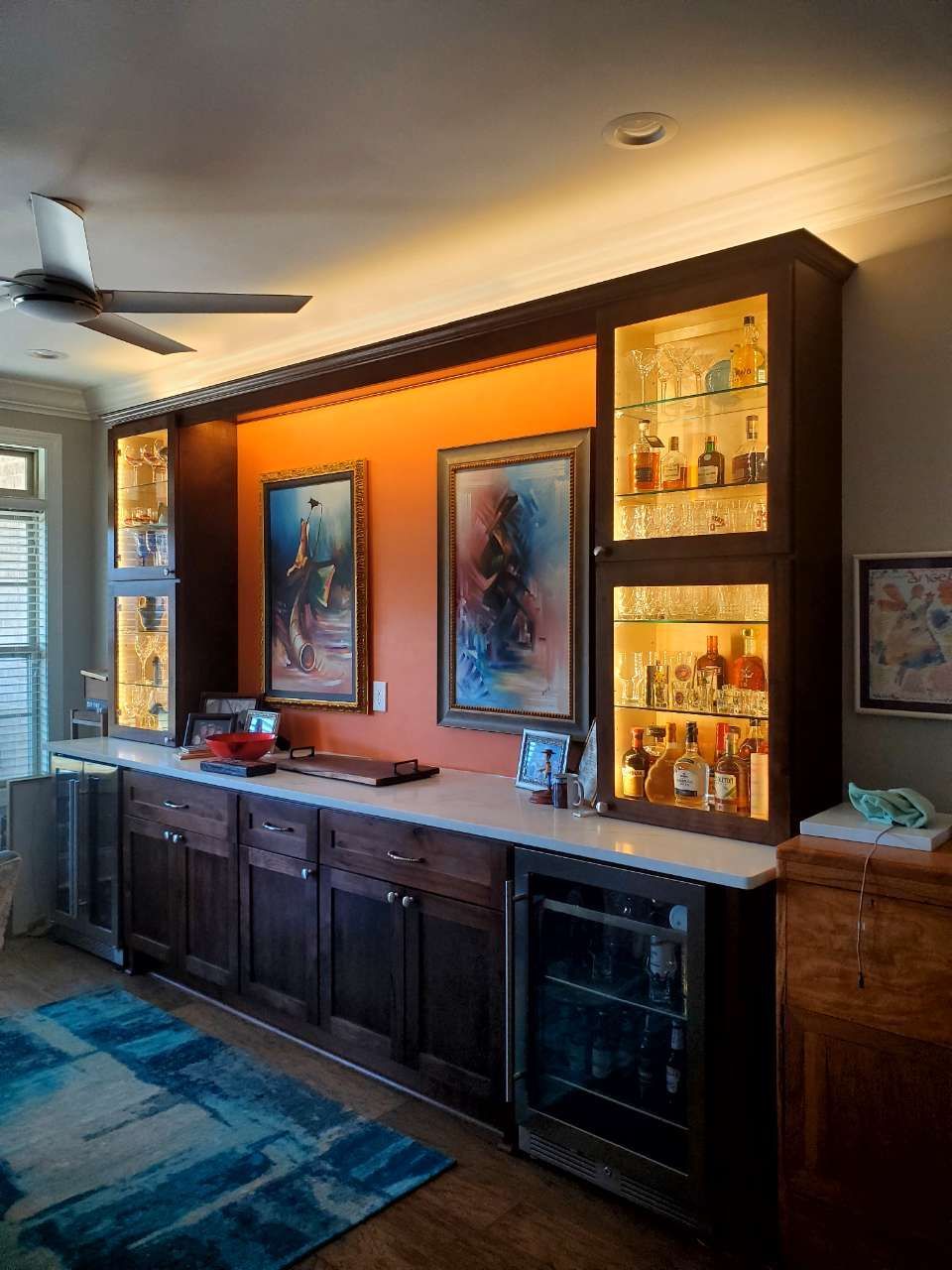 A living room with a bar and a refrigerator.