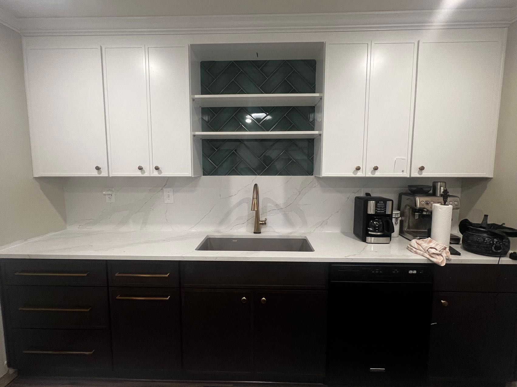 A kitchen with white cabinets, black cabinets, a sink, and a dishwasher.