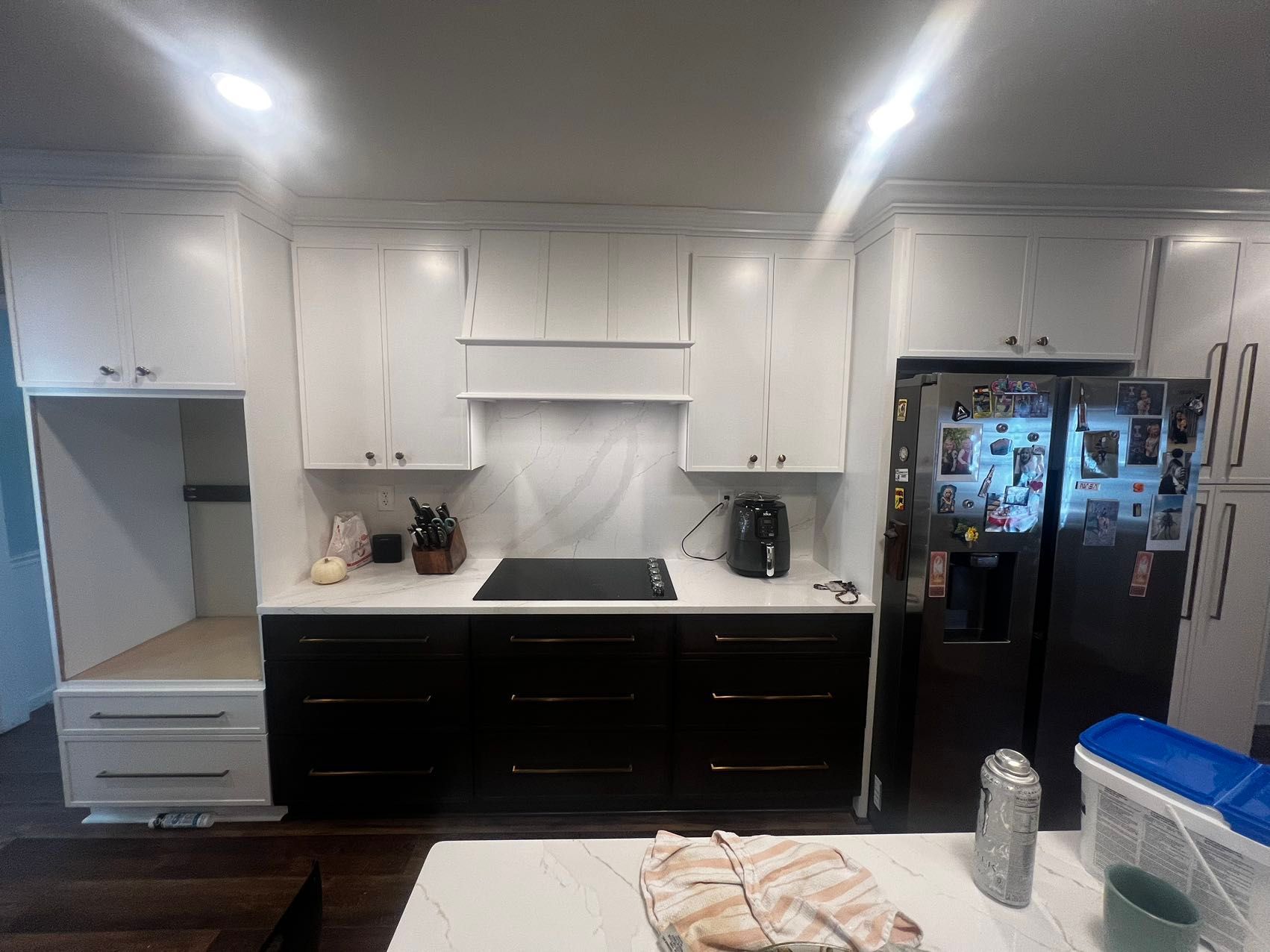 A kitchen with black and white cabinets, a stove top oven, a refrigerator, and a sink.