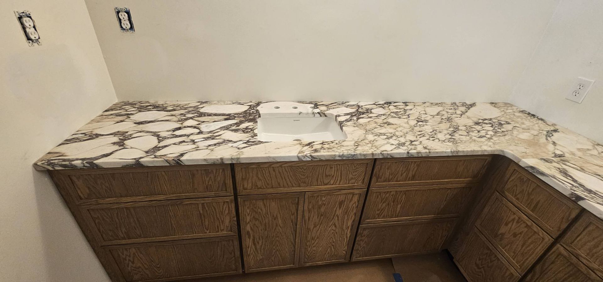 A kitchen with granite counter tops and wooden cabinets and a sink.