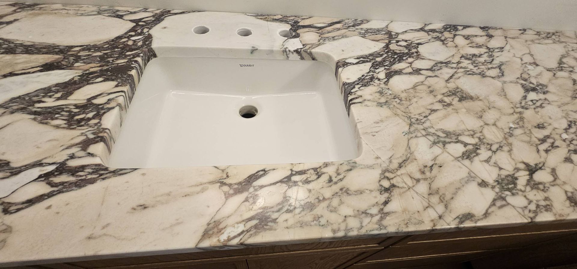 A bathroom sink is sitting on top of a marble counter top.