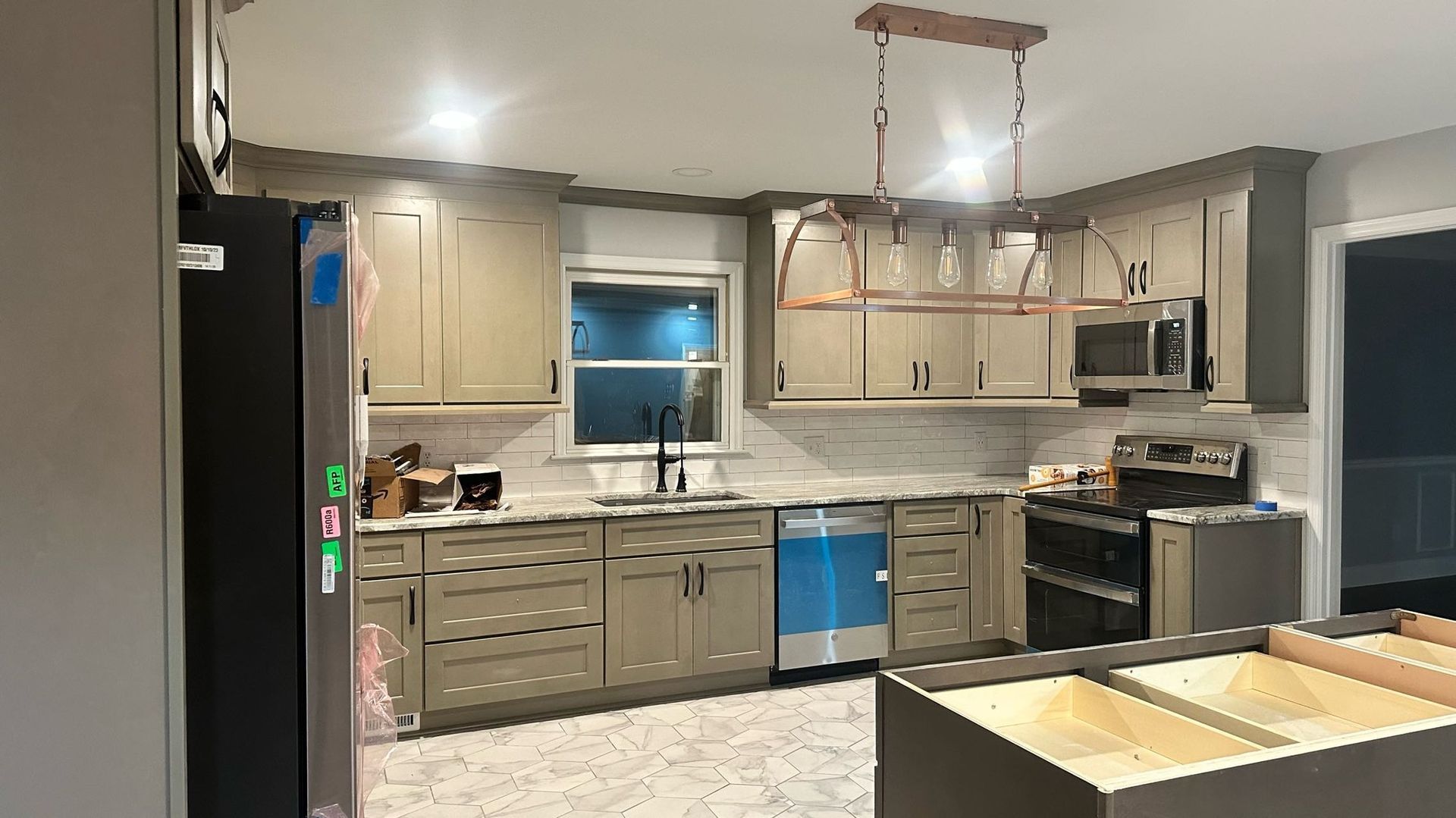 A kitchen with a stove, refrigerator, microwave, and sink.