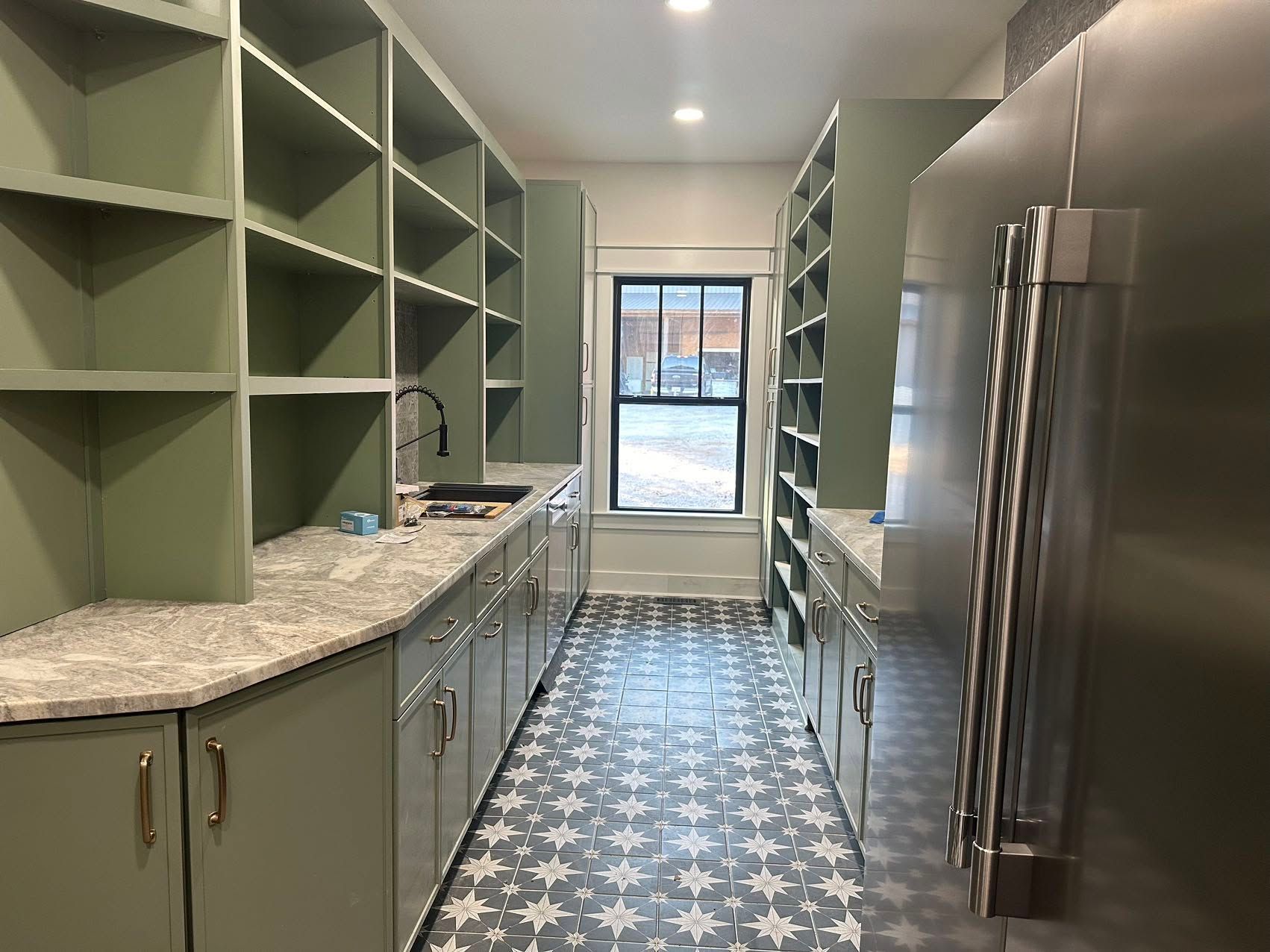 A kitchen with green cabinets and stainless steel appliances.
