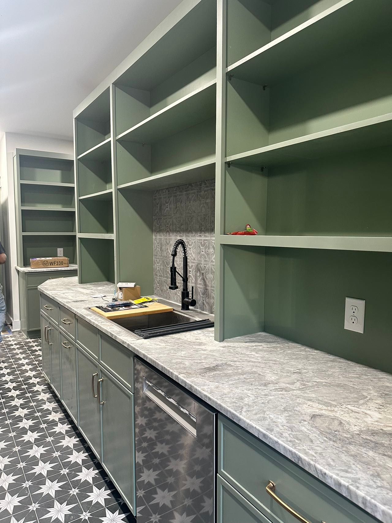 A kitchen with green cabinets and white counter tops.