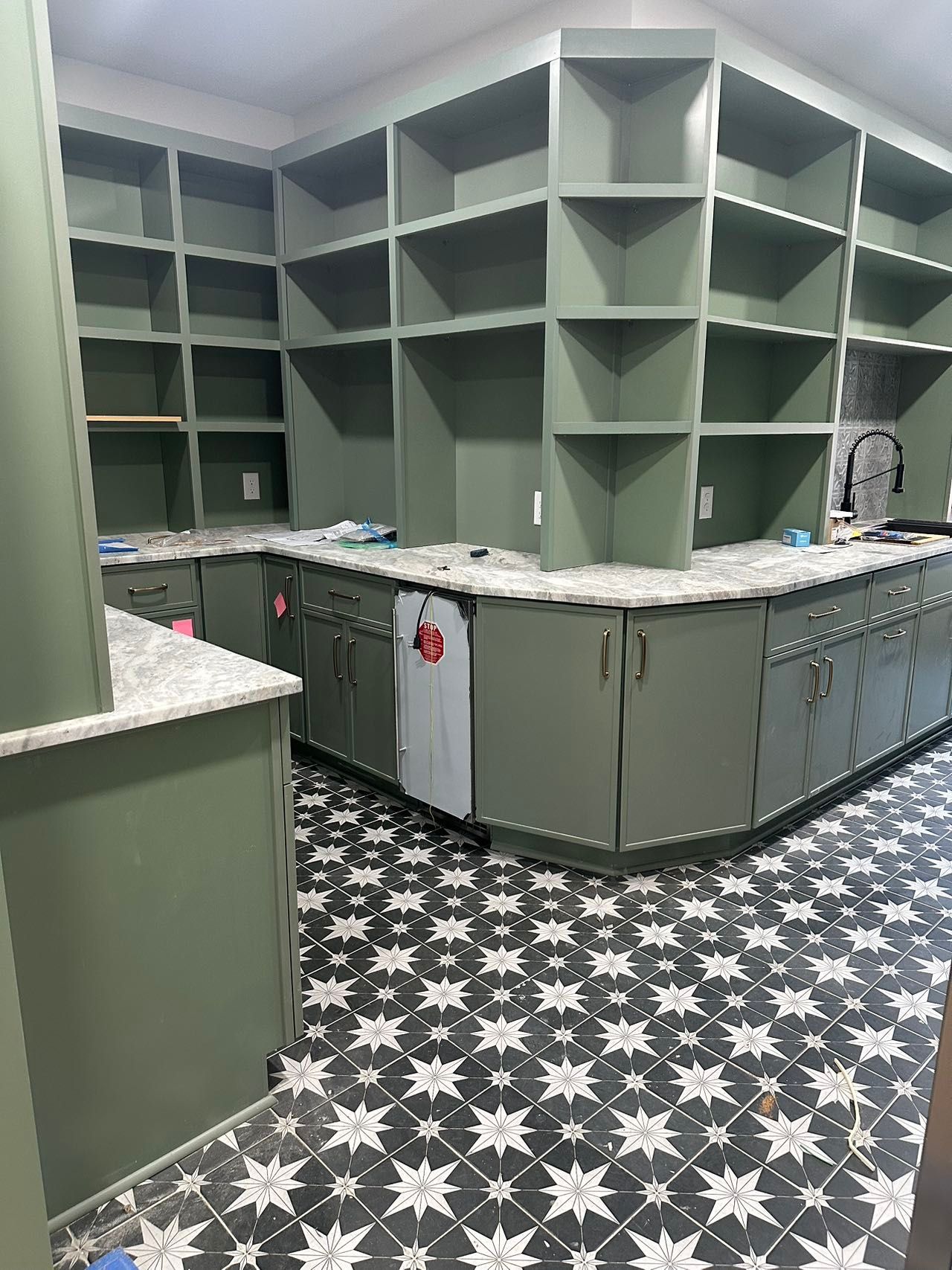 A kitchen with green cabinets and a black and white tile floor.