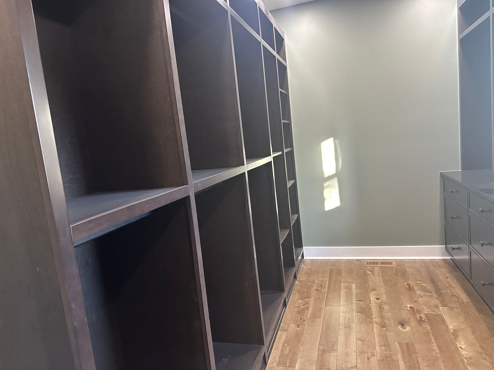 A room with a lot of shelves and a window.