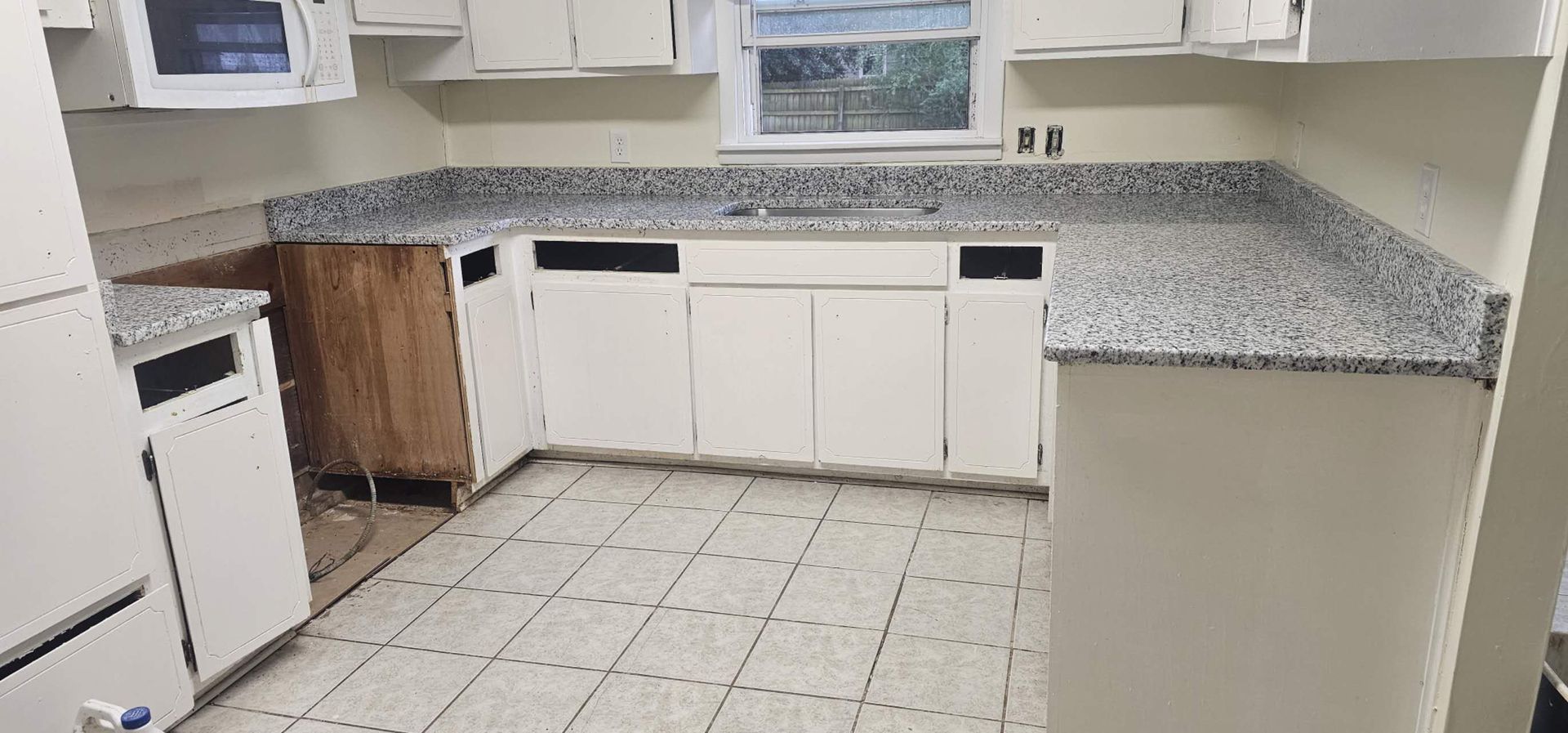 A kitchen with granite counter tops and white cabinets.